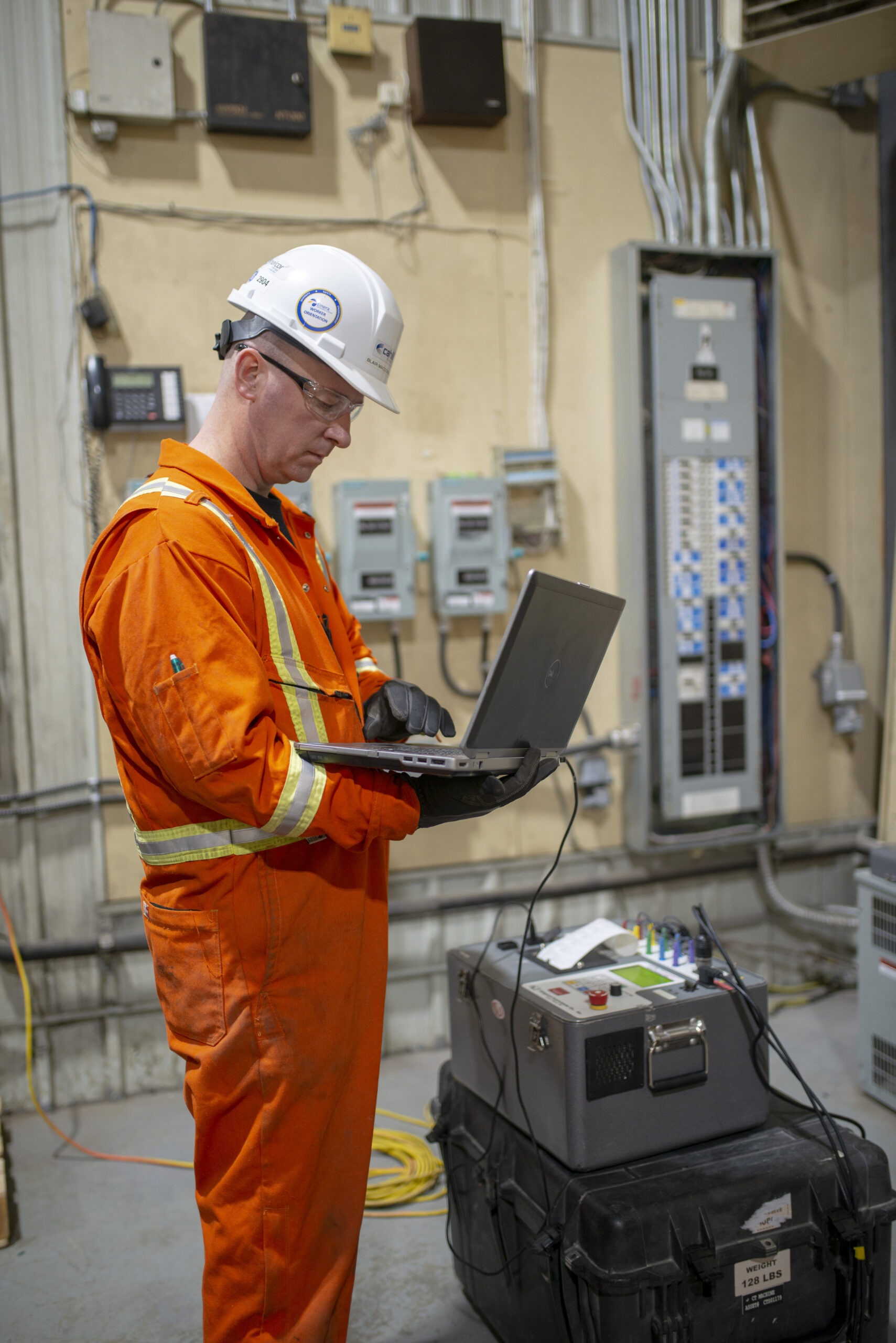 Technician testing electrical equipment with a laptop