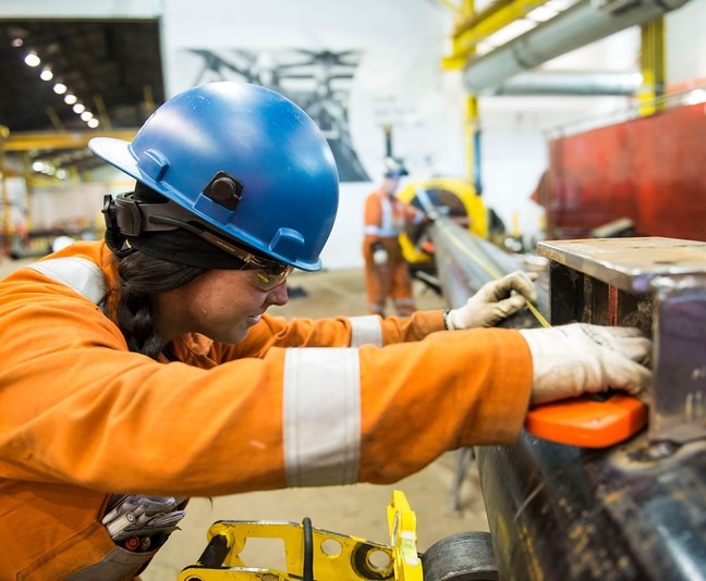 Technician measuring pipe in an industrial workshop