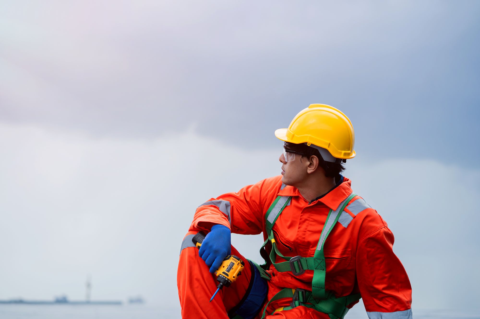Offshore worker in coveralls looking out over the ocean